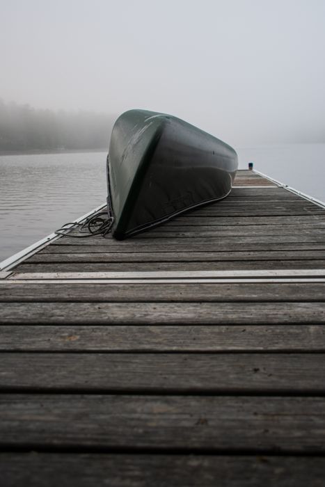 A canoe resting on a foggy dock in the early morning