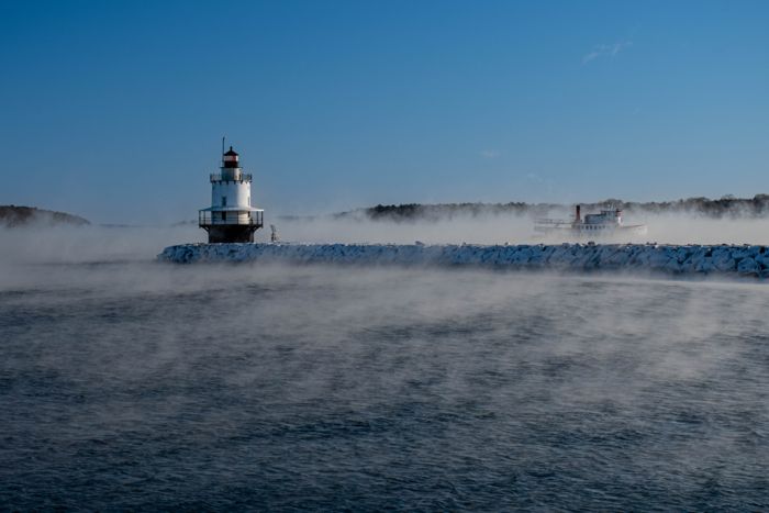 Spring Point Ledge lighthouse surrounded by sea smoke on a cold clear morning